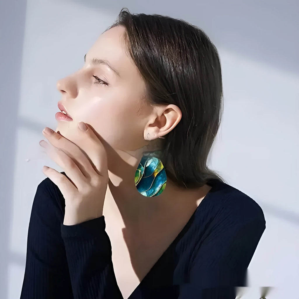 A pair of printed acrylic earrings with a flat branch knot design in a drop shape.