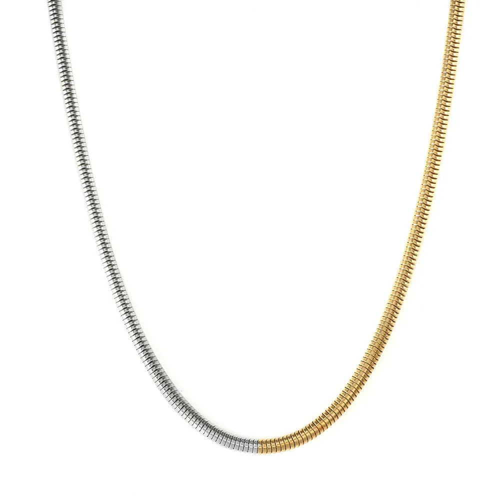 Golden stainless steel snake bone chain necklace with lobster clasp on a dark background.