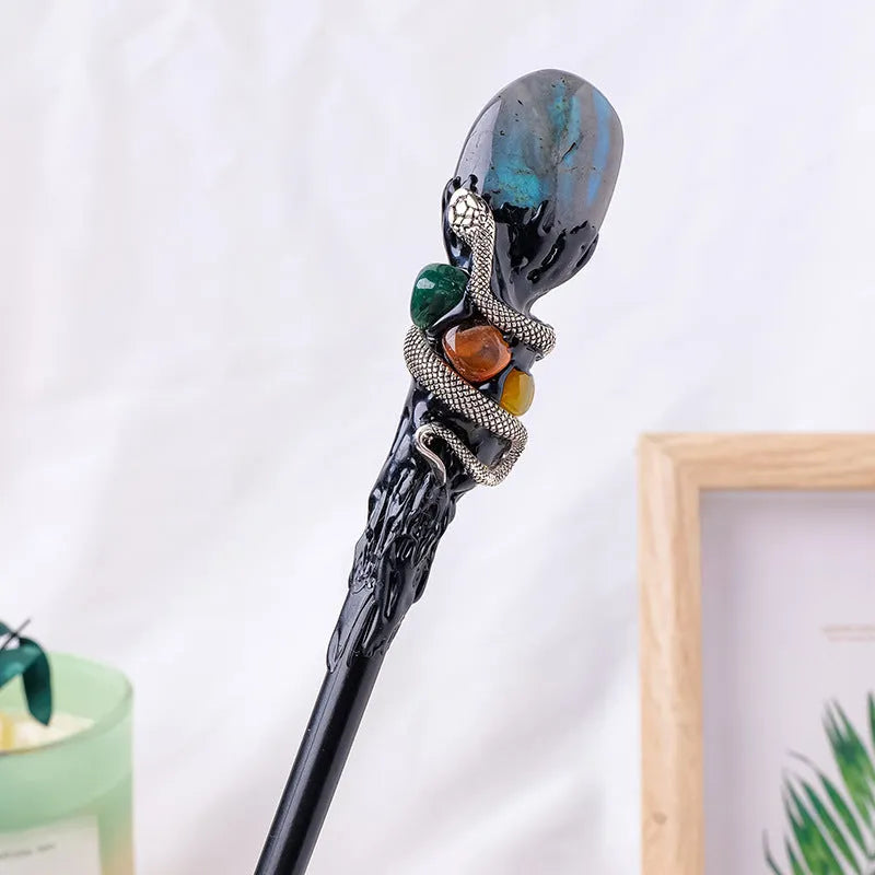 Natural crystal magic wand with labradorite stone ball on simple handle against neutral background