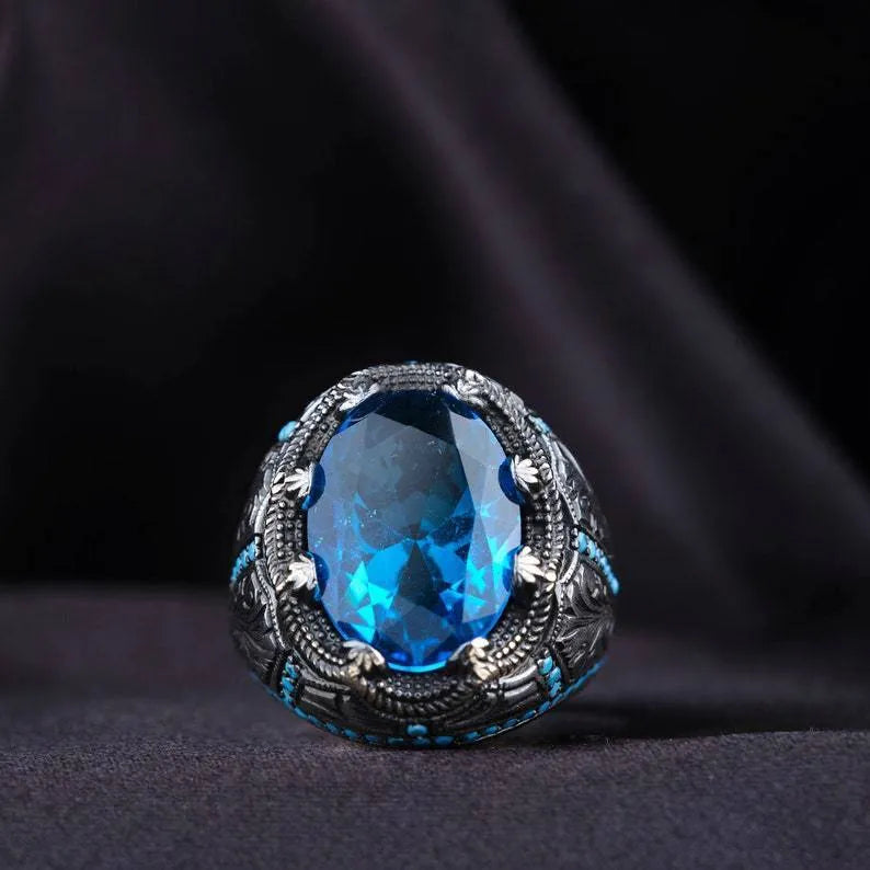 Geometric antique silver unisex ring with a central blue zircon stone on a finger.