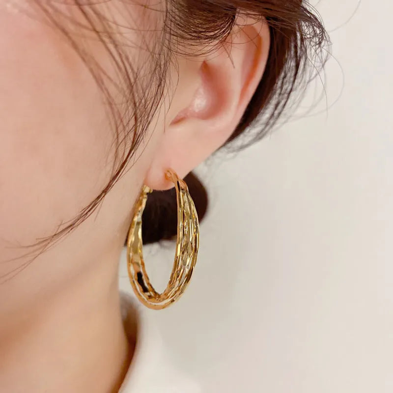 Gold and silver twisted metal earrings with copper body, round geometric shape, and silver needle for women.