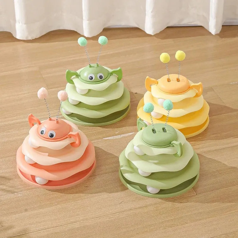 Cat toy tower with rotating bee toy and three-layer trackball in green plastic, placed on a wooden floor
