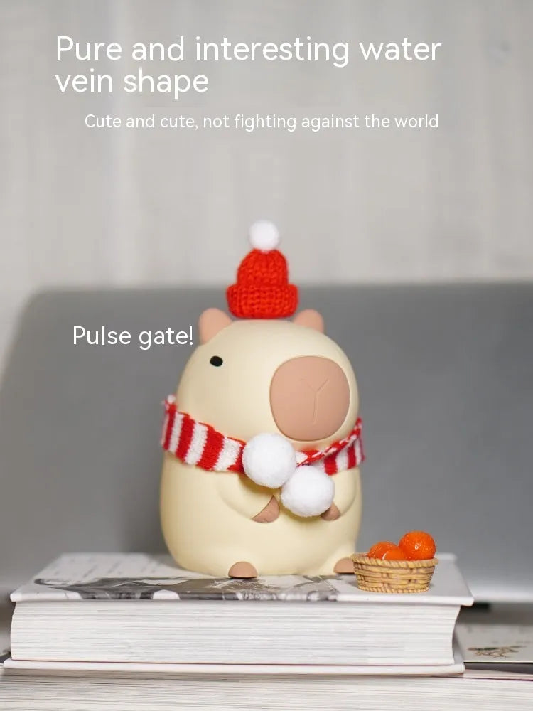 Small capybara-shaped night lamp in silicone and plastic, shown with USB cable.