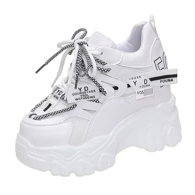 Women's white mesh platform sports shoe with cross strap and rubber sole on a neutral background.