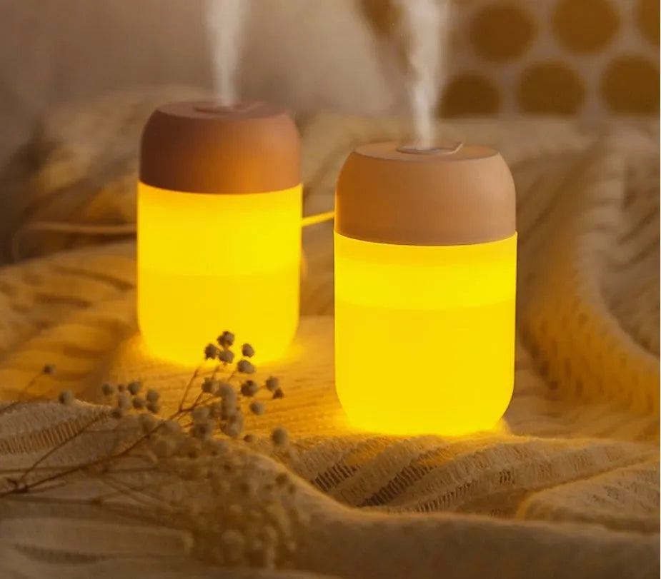 White cylindrical mini humidifier with USB cable on a wooden surface.
