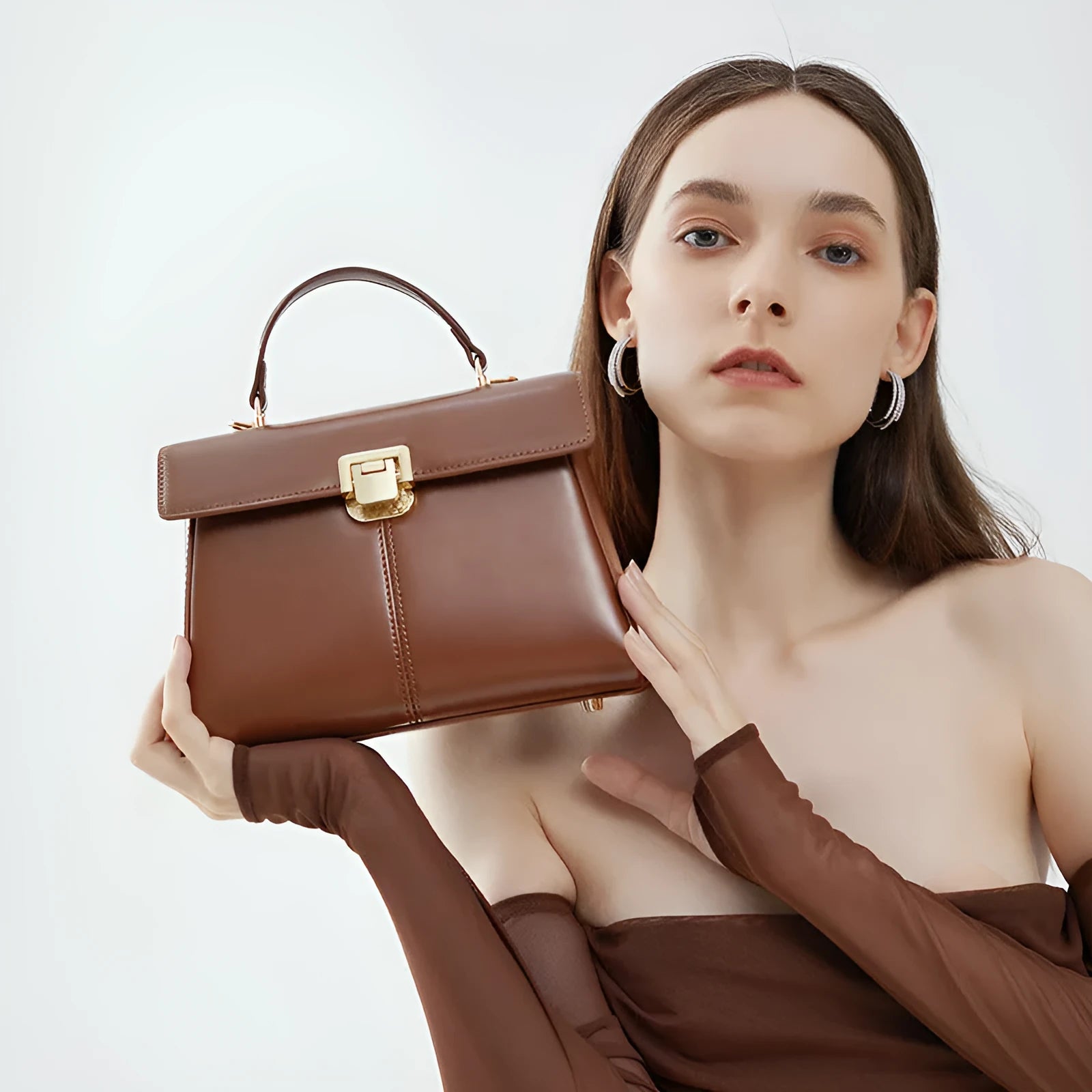 Black genuine leather women's shoulder bag with vachette clasp, showing horizontal square shape and adjustable strap.