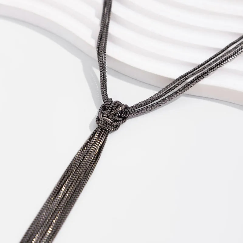 Simple Y-shaped metal tassel necklace set with gold finish and matching earrings on white background
