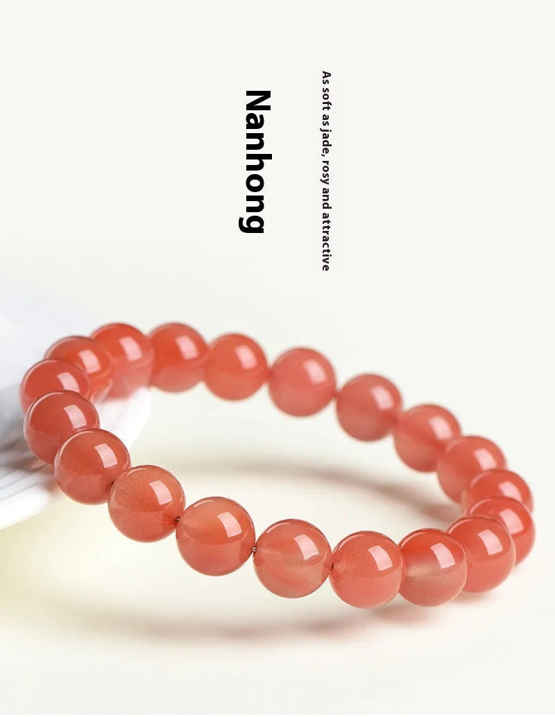 Natural cherry red agate bracelet with hand-polished beads on a wrist, showing colour variation and secure clasp.