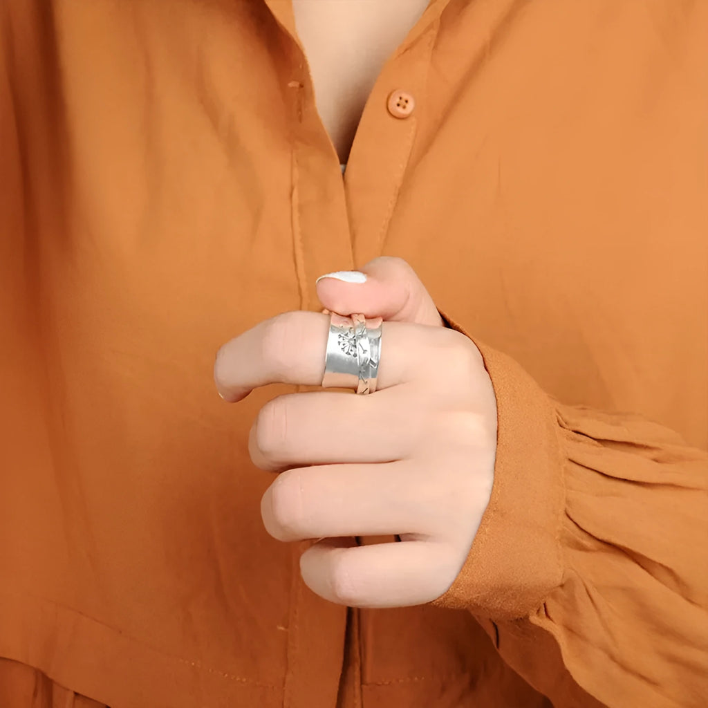 Silver-coloured rotatable flower fashion ring on a finger, showing the floral detail.