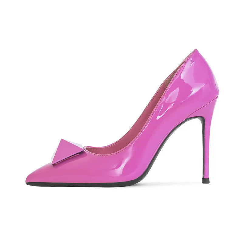 Women's pink patent leather pointed toe stiletto heels with buckle and rivet detail on a shallow cut.