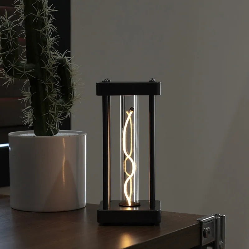Metallic gray acrylic square night lamp with curved wire on a desk