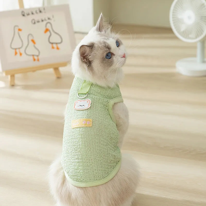 Green knitted cat clothing with a cartoon bear patch, showing hollowed-out breathable fabric.
