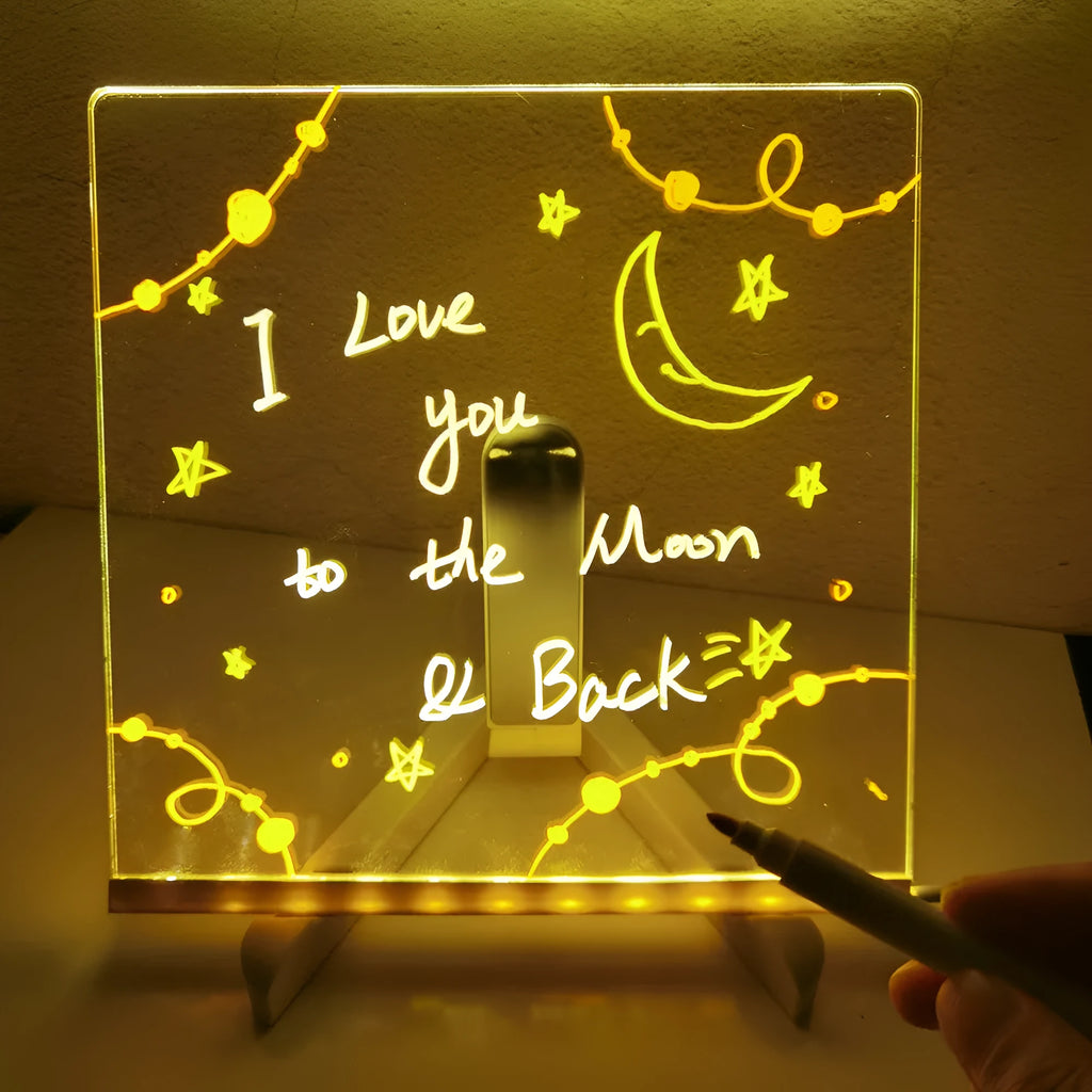 Acrylic DIY LED message board on a bracket, glowing softly with handwritten notes, alongside white and colourful pens.