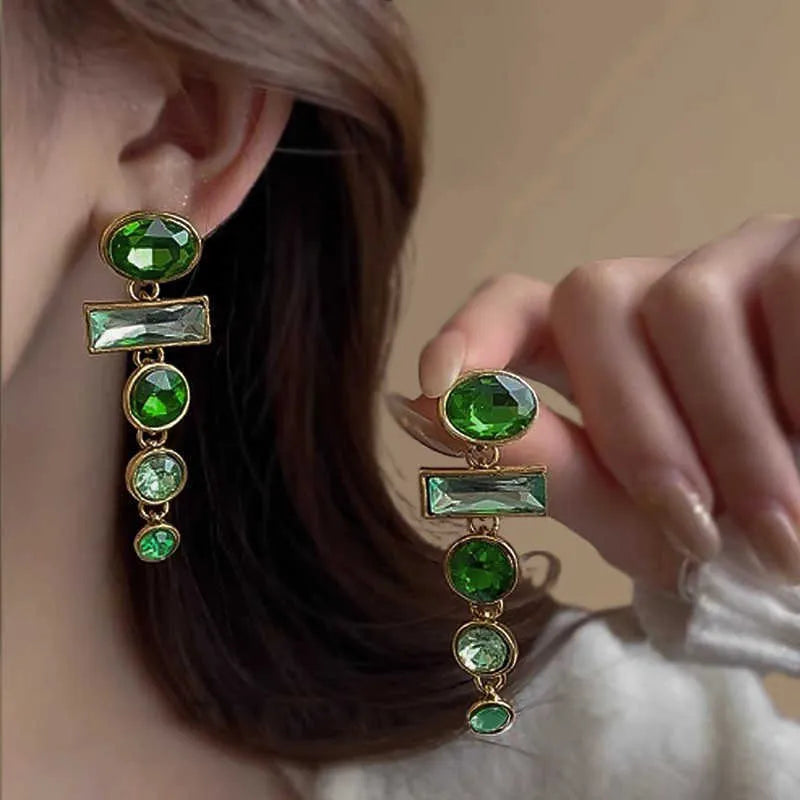 Green gradient geometric alloy earrings with a long tassel and sparkling inlaid zircon centre on a white background.