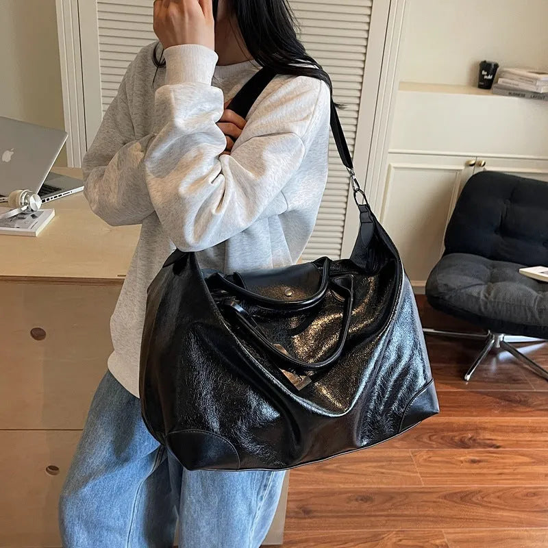 36-55L capacity hand-carry travel bag in black or silver with PU construction and polyester lining