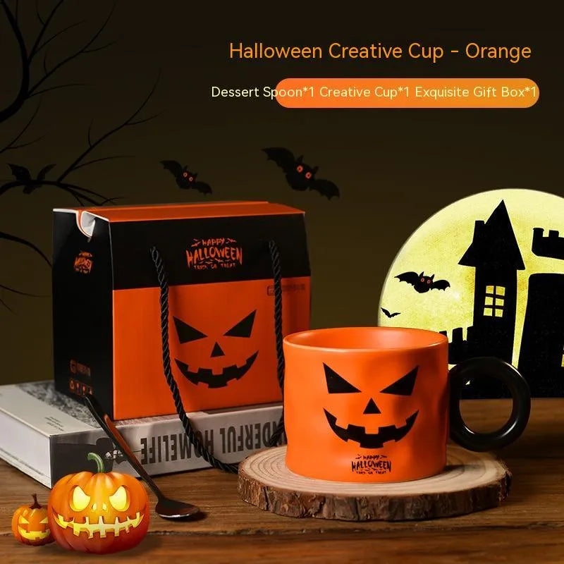 Orange ceramic Halloween pumpkin cup with handle beside dessert spoon in gift box
