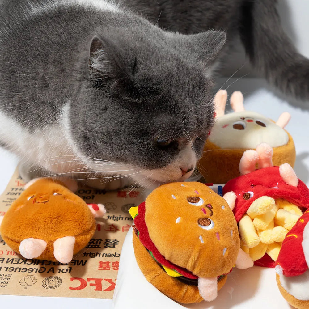 Five cat teething toys shaped like hamburger, chicken leg, fries, hot dog and bread on white background