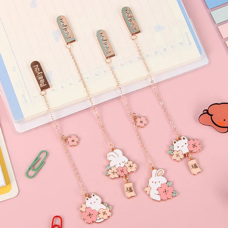 Small metal bookmark pendant with cherry blossom and cartoon cat or rabbit design.