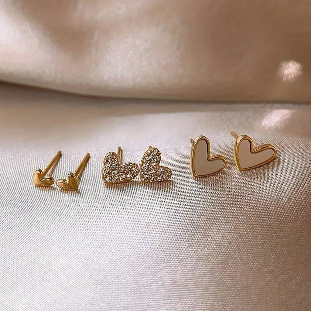 Three pairs of girly heart-shaped alloy earrings in gold, black, pink, and black and white colours.