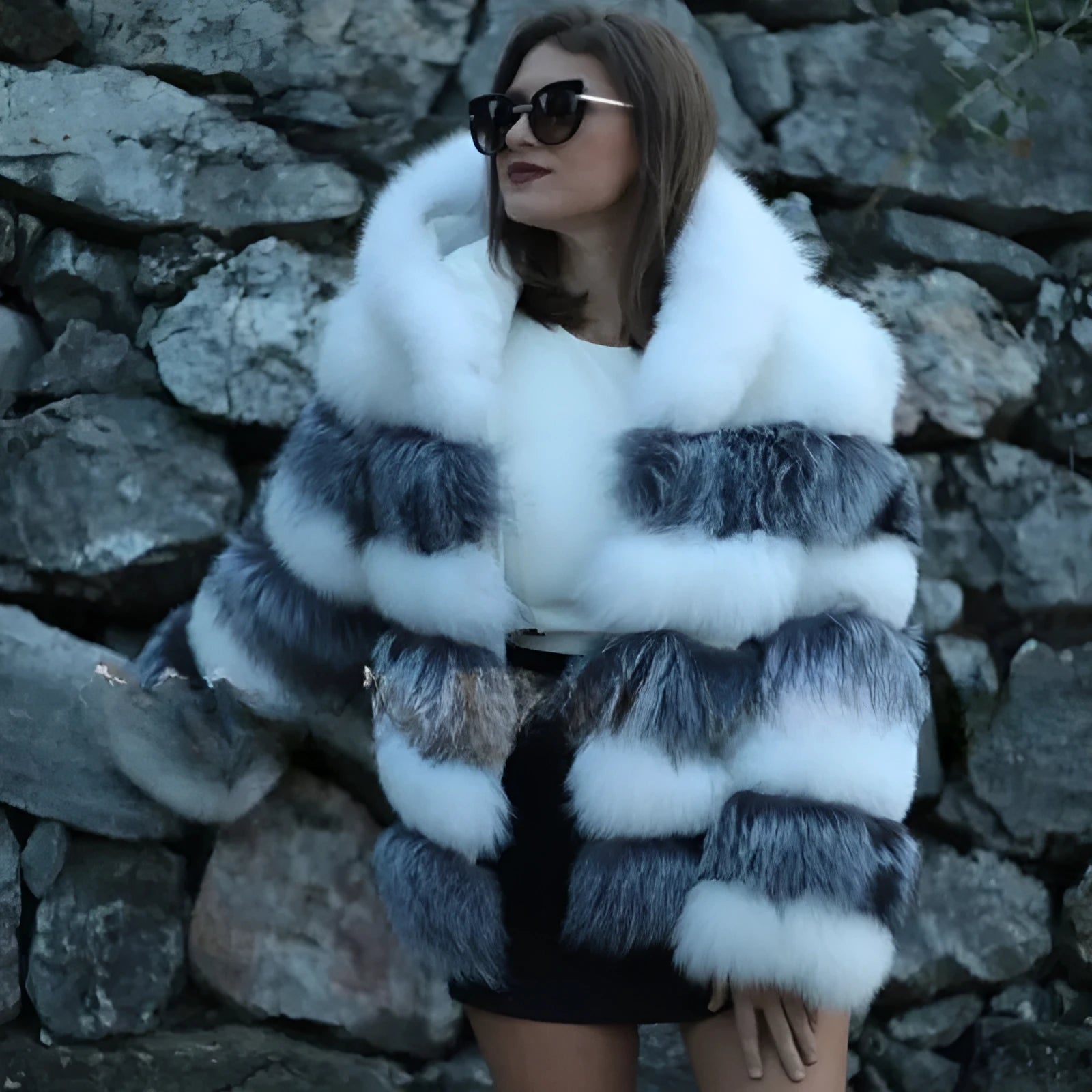 A woman modelling a loose-fitting, hooded artificial fur coat in a street fashion style.