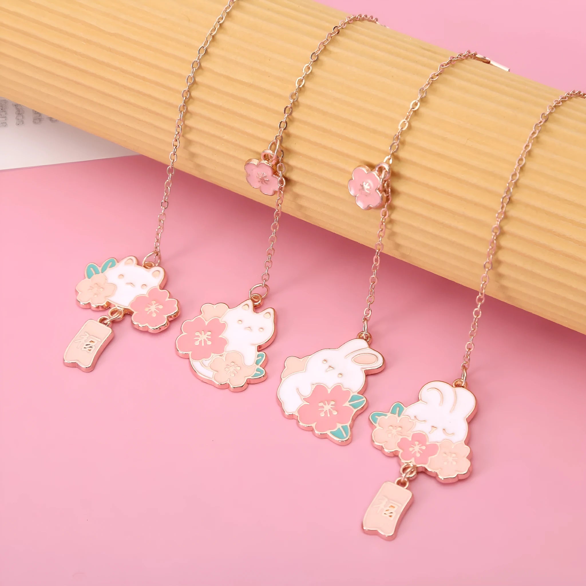 Small metal bookmark pendant with cherry blossom and cartoon cat or rabbit design.