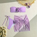 Blue women's swimsuit set with 3D flower, bikini bottoms, and a separate wrap skirt laid flat.