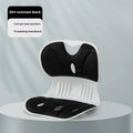 Black memory foam chair backrest cushion with a white fixing strap, shown on an office chair.