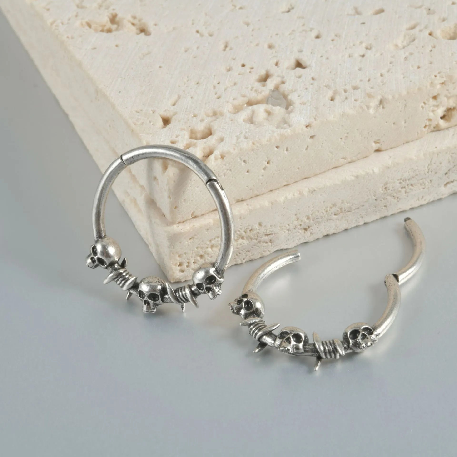 Close-up of vintage-style copper ghost head earrings with antique silver plating on a dark background.