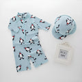 Boy's penguin print long sleeve swimsuit top and matching swim cap set on blue background