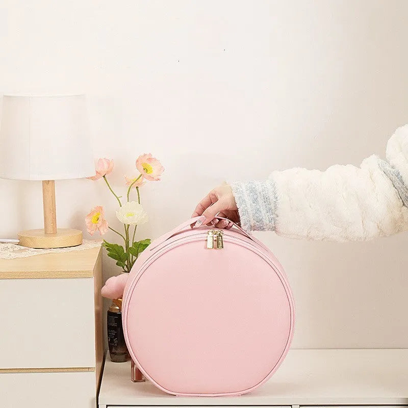 Round pink PU leather makeup bag open showing illuminated mirror and internal partitions.