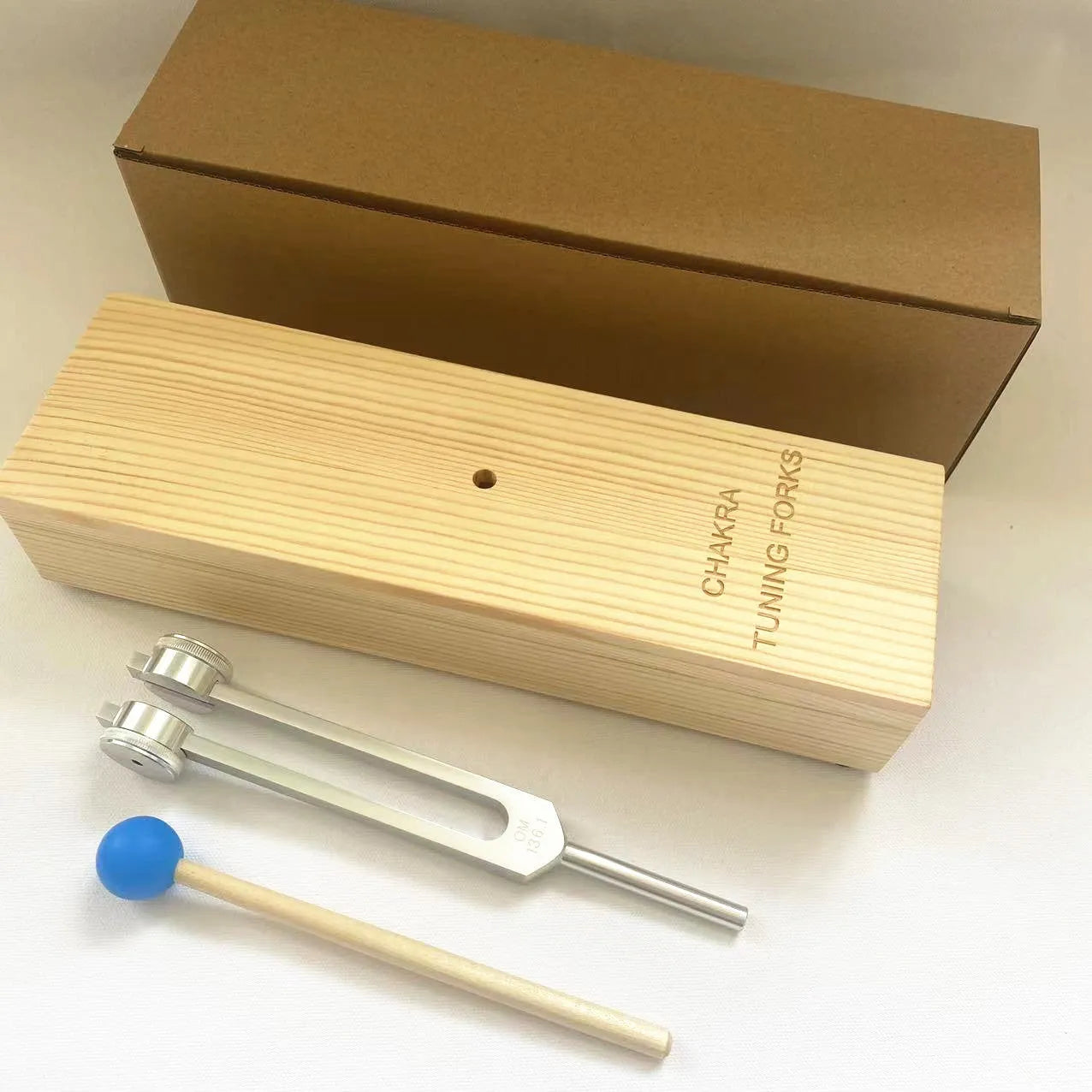 Aluminium alloy 432Hz tuning fork and speaker set on a kraft paper box.