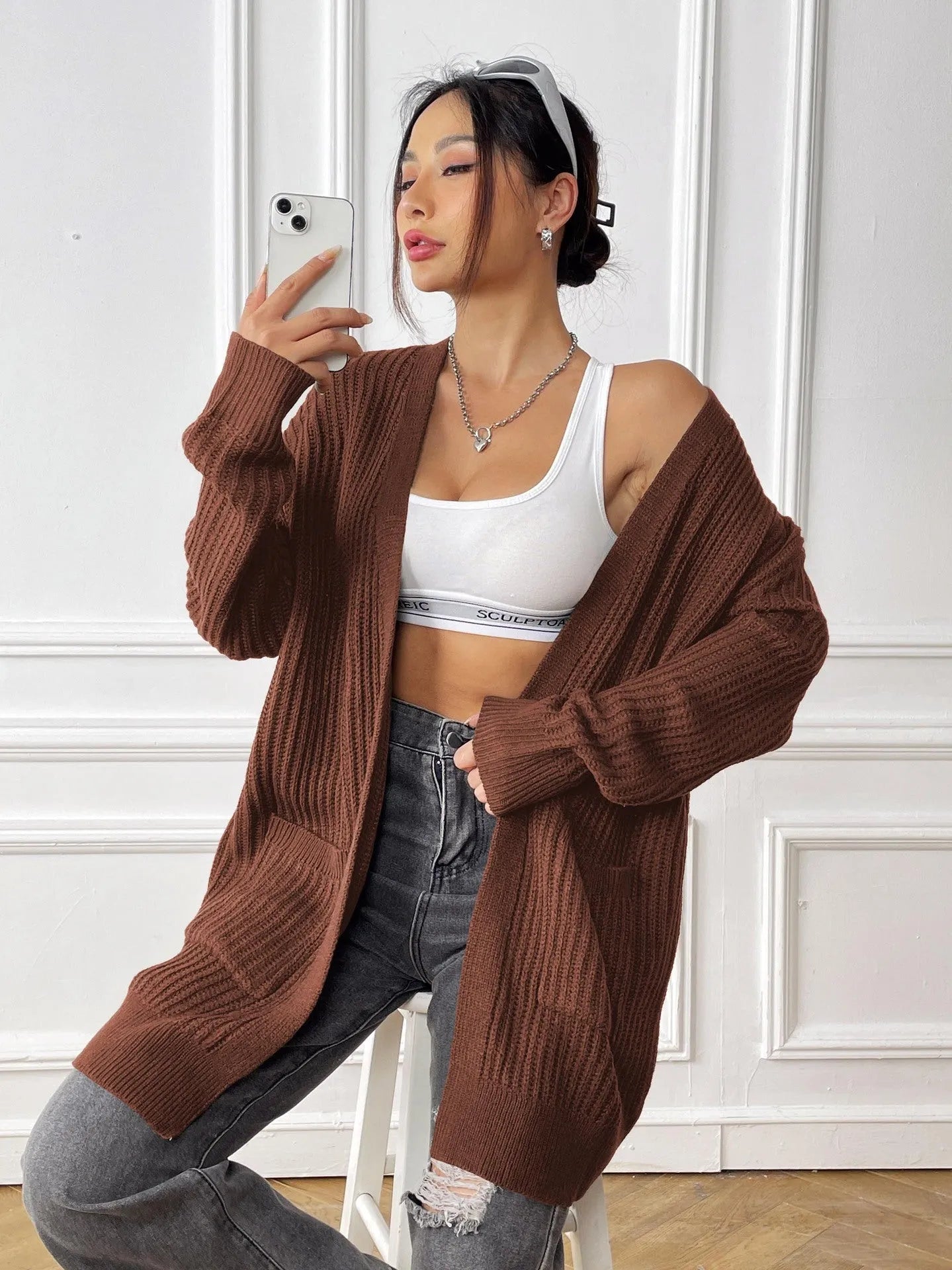 A dark green loose-fit women's cardigan sweater with two front pockets and long sleeves.