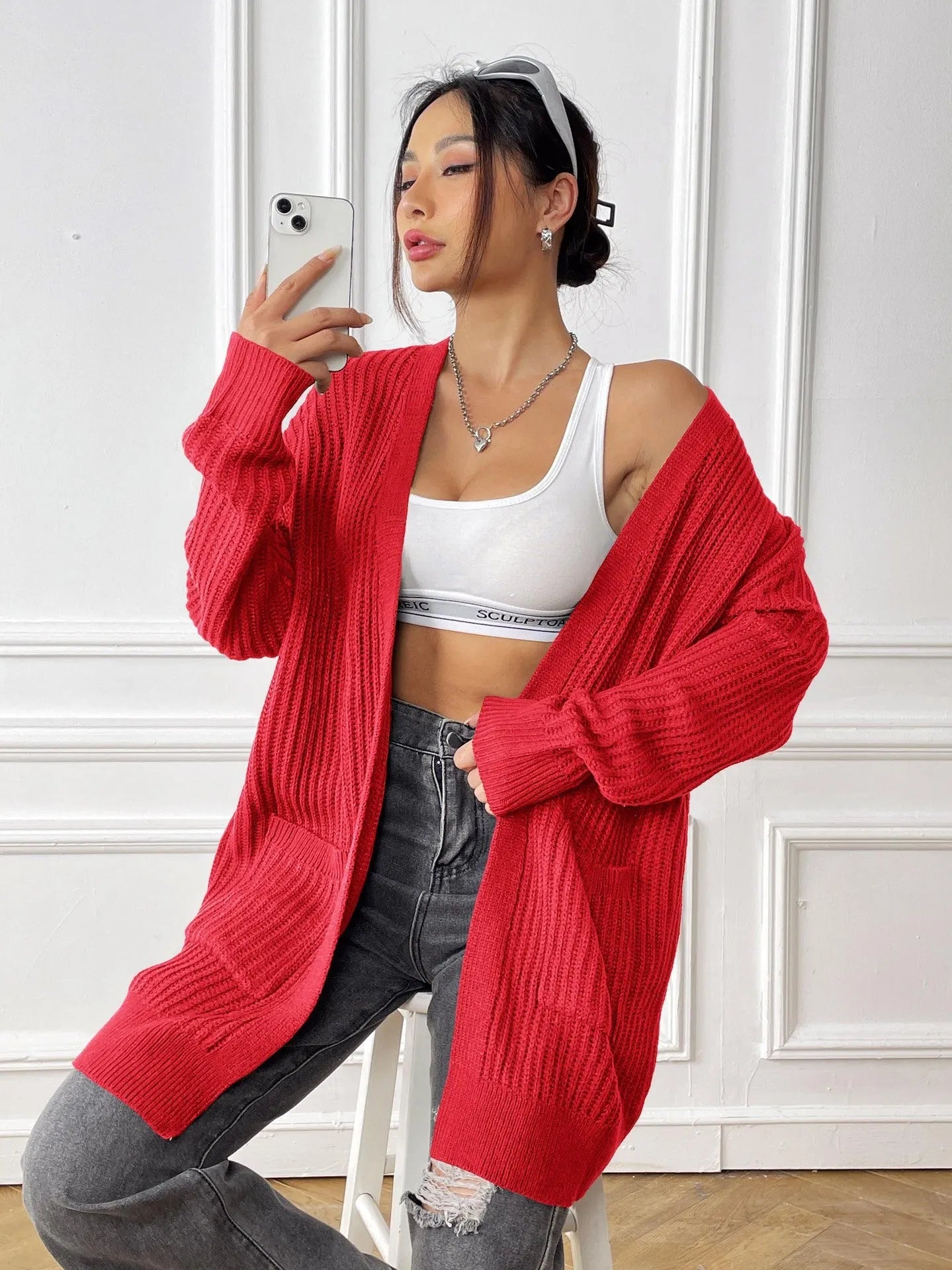 A dark green loose-fit women's cardigan sweater with two front pockets and long sleeves.