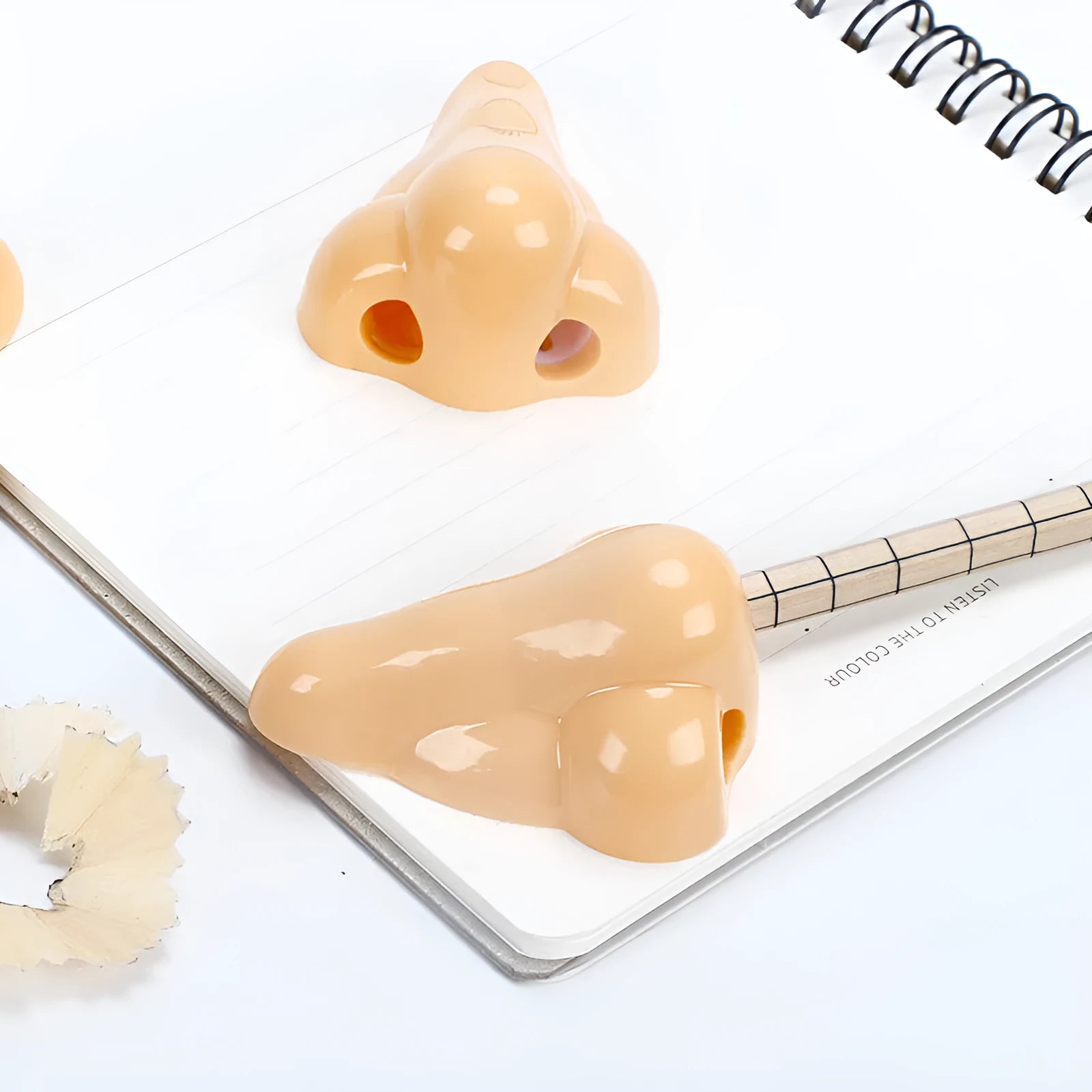 Flesh-coloured plastic manual pencil sharpener with a geometry shape and large nostril.