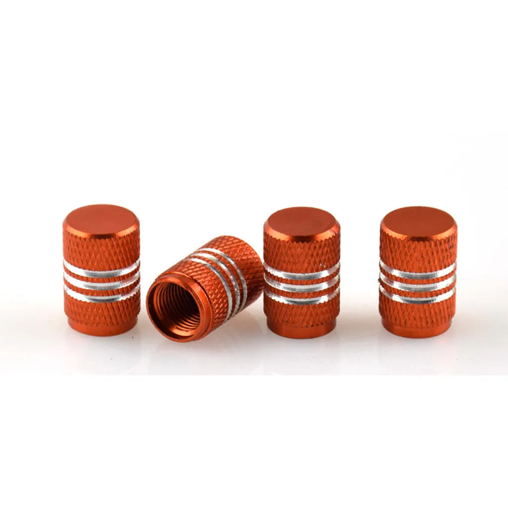 Set of coloured aluminium alloy tyre valve caps for car wheels on a grey background.