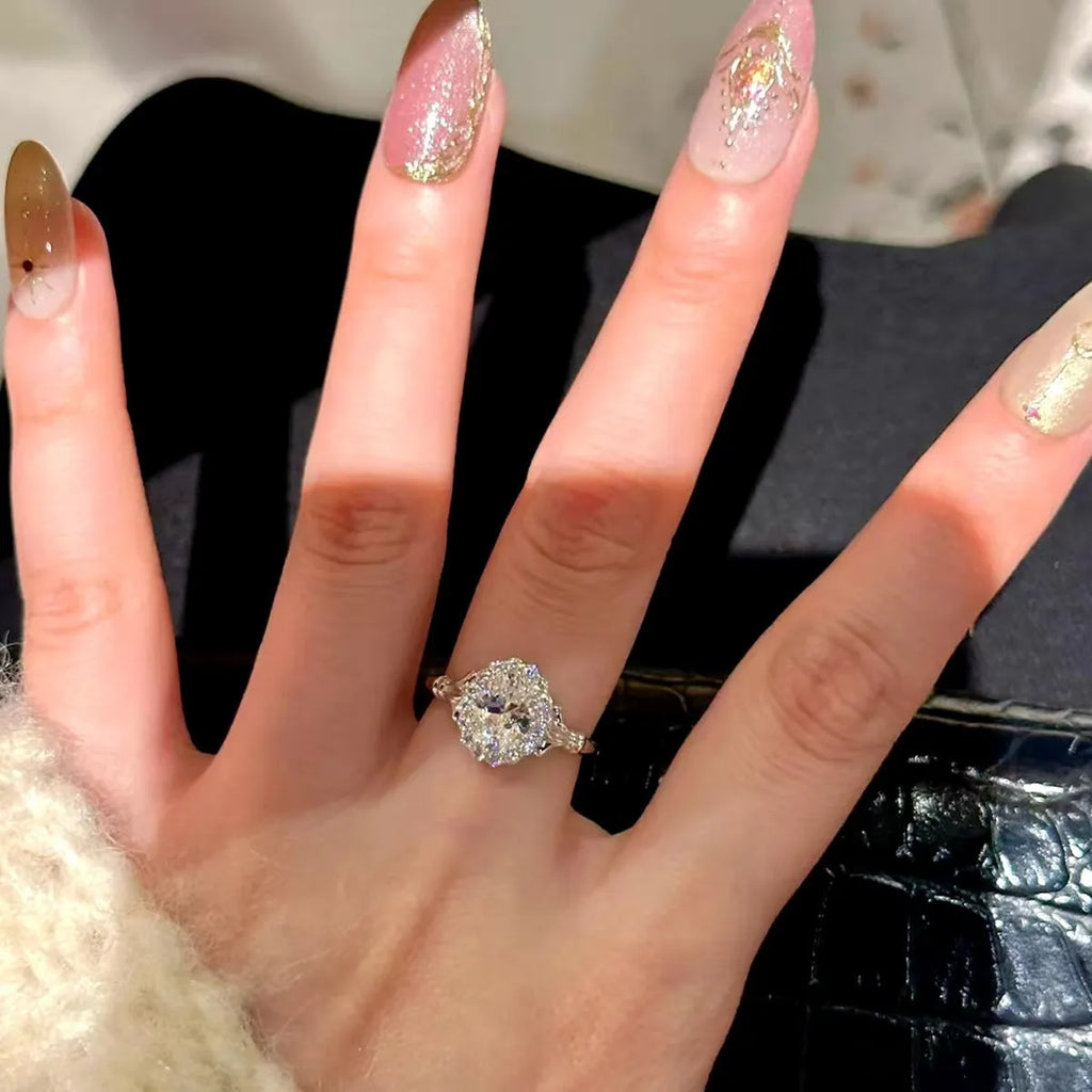 Close-up of a silver geometric ring with a large elliptical diamond on an adjustable open band.
