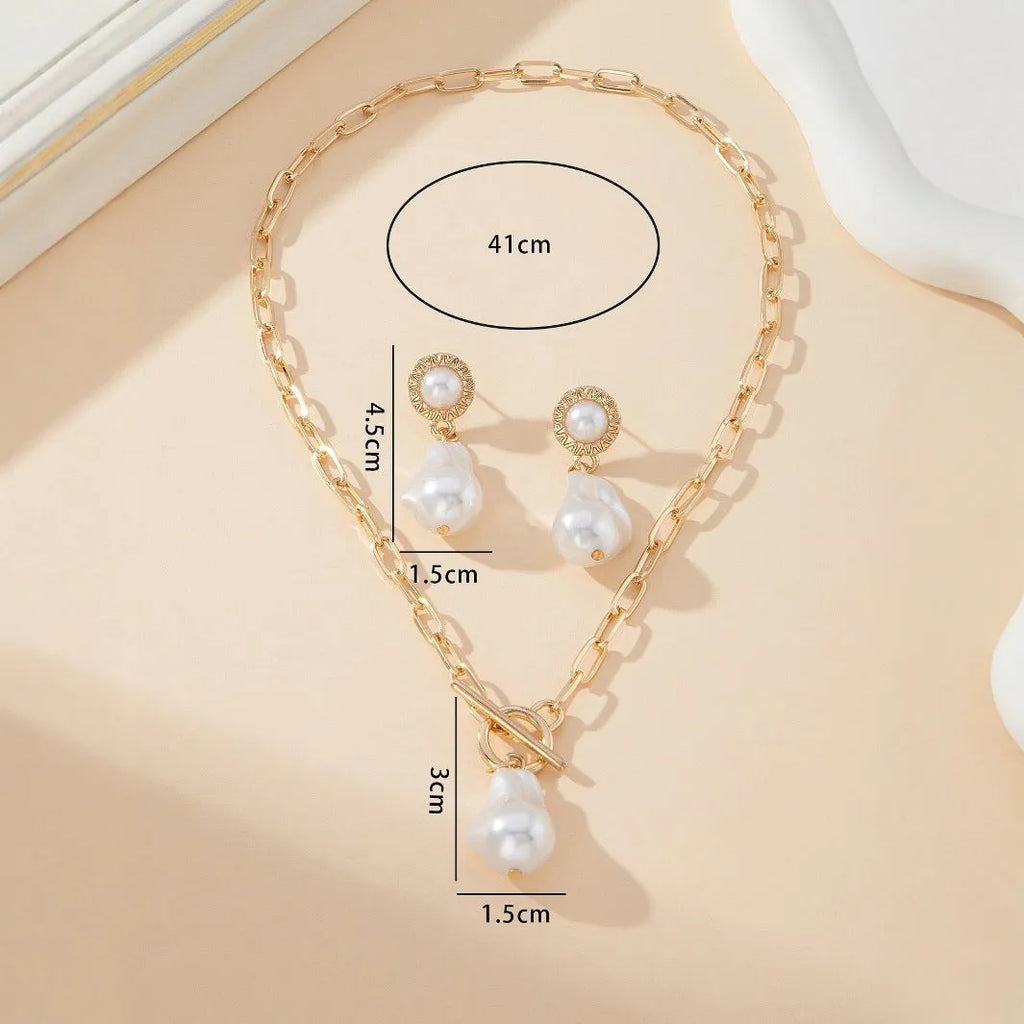 Gold baroque pearl pendant necklace and matching ear stud jewellery set on white background