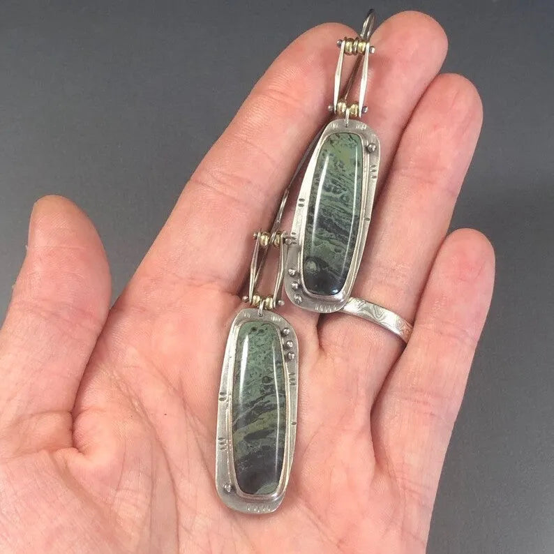 A pair of geometric-shaped alloy earrings with a white and grey marble pattern.