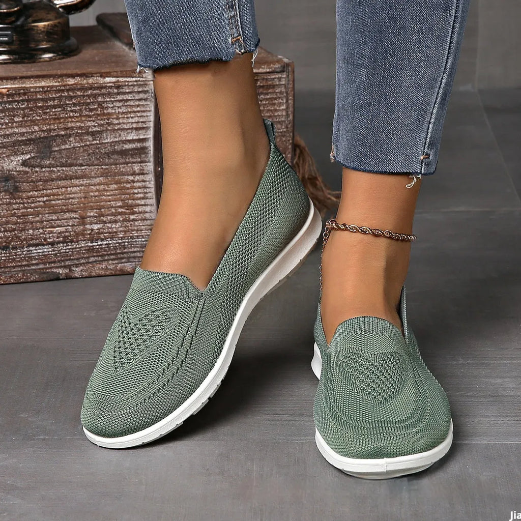 Women's beige canvas flat shoes with a heart pattern, mesh lining, and a flat rubber sole.