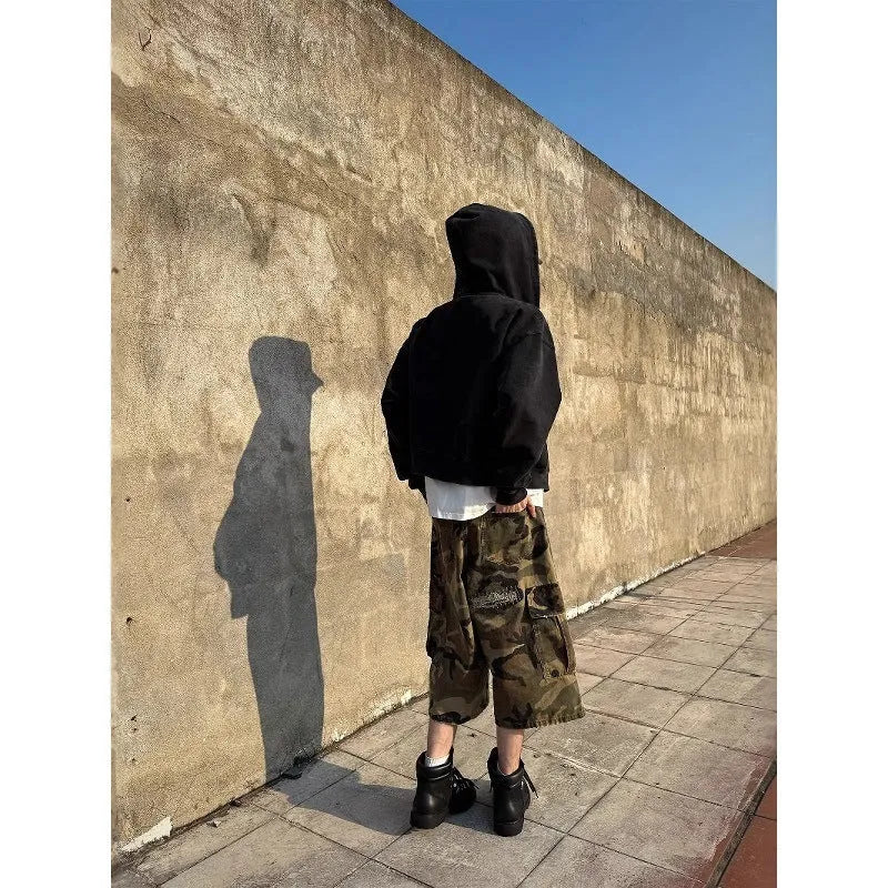 Men's loose-fit camouflage cropped jeans with ripped details and patches on a straight leg.