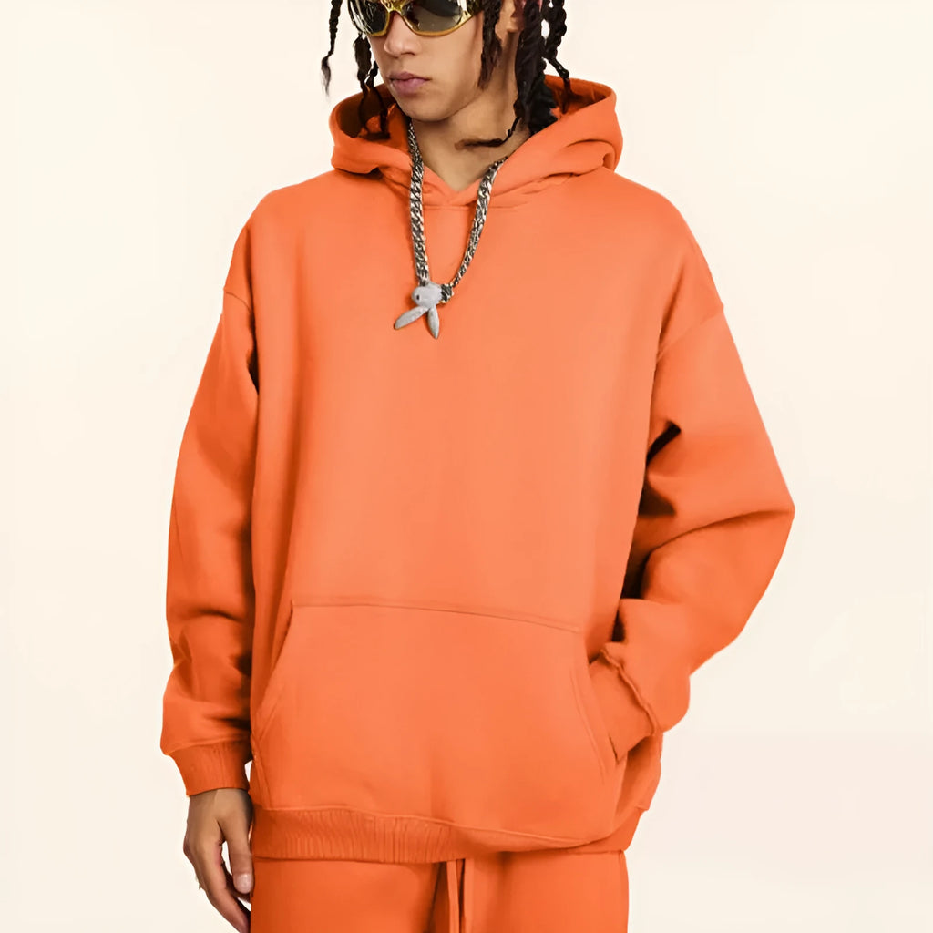 Man wearing a loose-fit cotton terry hooded sweater in a grey apricot colour.