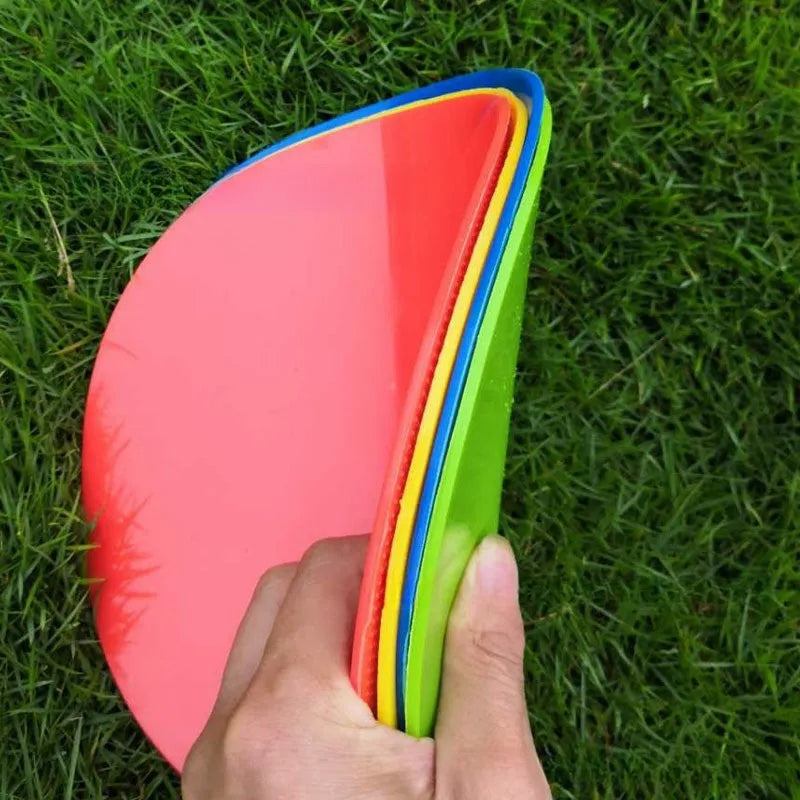 Soft yellow TPE football training target pad flat on grass, 23cm diameter.