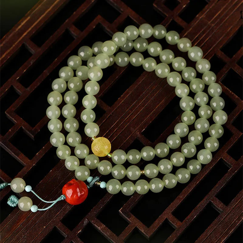 Pale blue Hetian jade bracelet with three circle design and 6mm beads on a wrist.