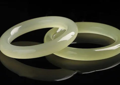 A close-up of a winding jade bracelet made from round bar beads on a wrist.