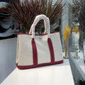 Women's canvas bucket tote bag with genuine leather trim showing internal zipper compartments and crossbody strap