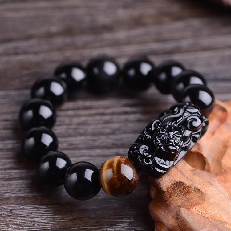 Natural obsidian Pi Xiu bracelet with hand-carved pendant on a flat surface, three bead sizes available