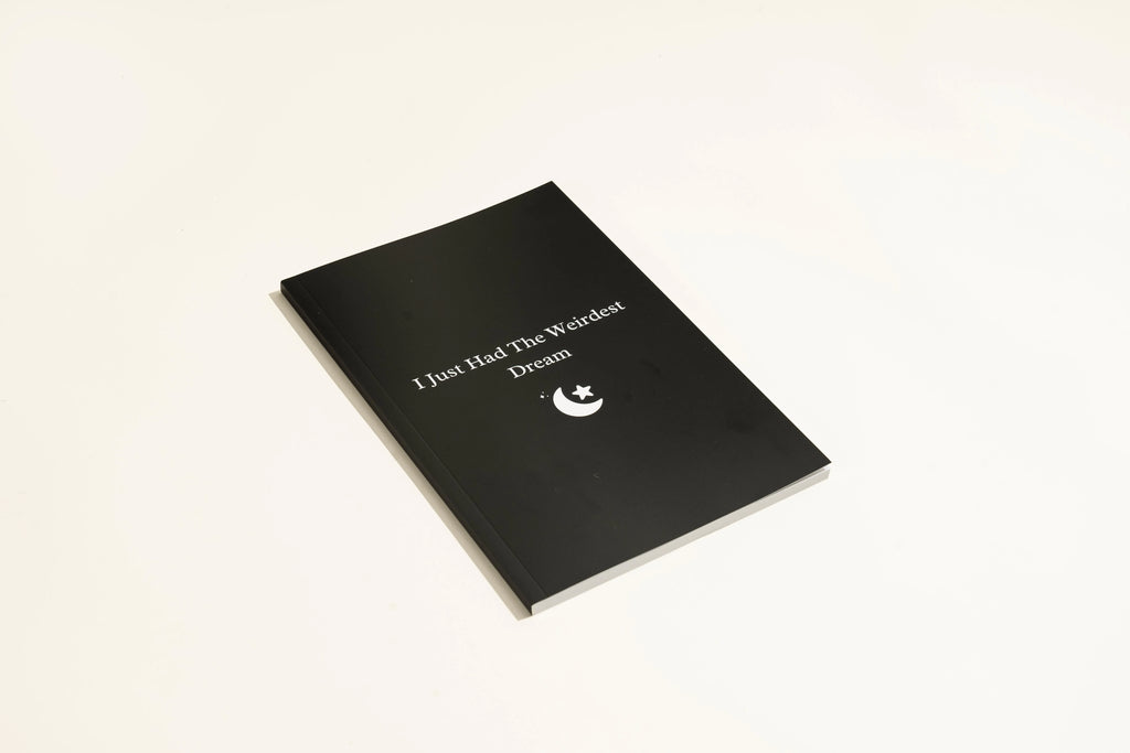 Black hardcover dream journal notebook with lined pages open.