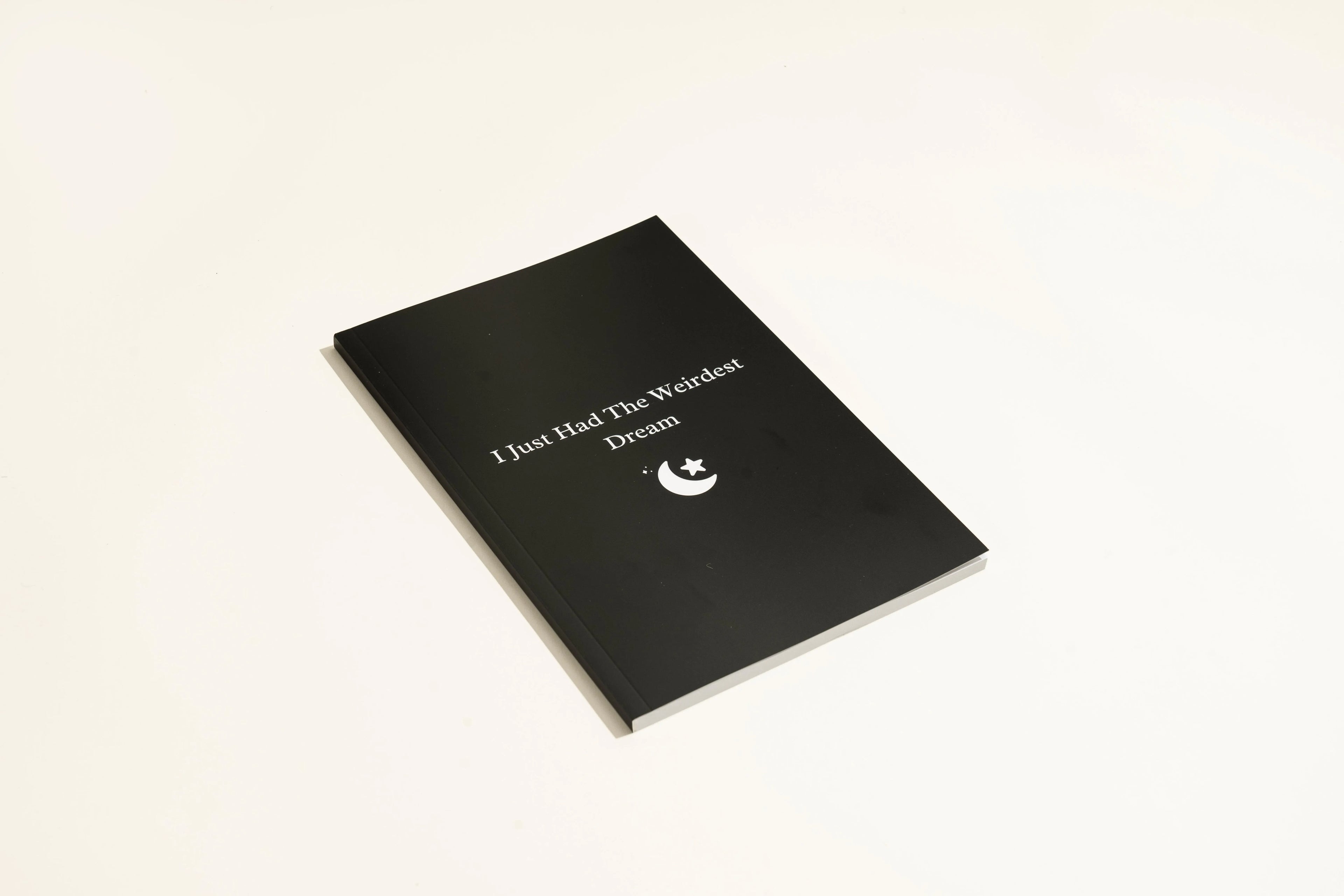 Black hardcover dream journal notebook with lined pages open.