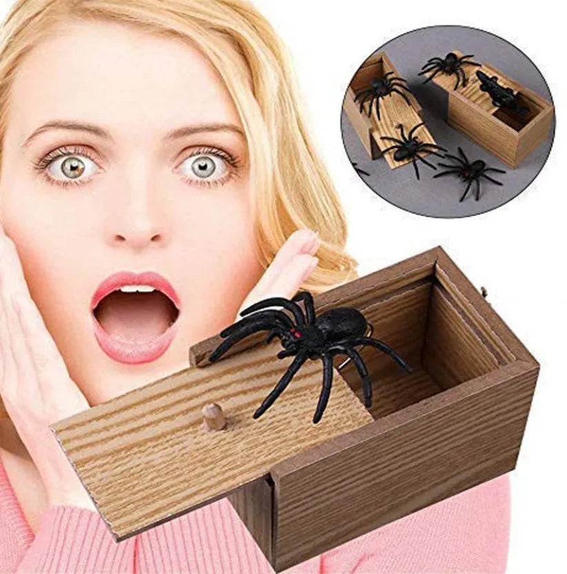 Wooden prank scare box closed, with a lifelike jumping spider toy next to it.