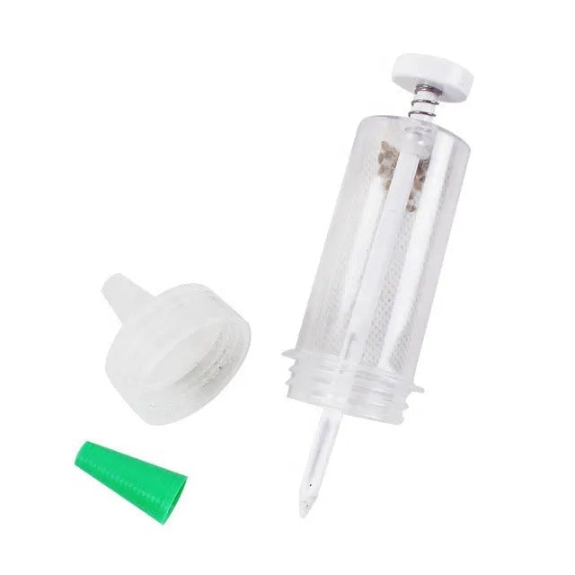 A white plastic mini garden seeder tool, 12cm long, for planting seeds in pots and trays.